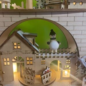 Charming Wooden Holiday Village with Snowman Figurine and Christmas Carol.